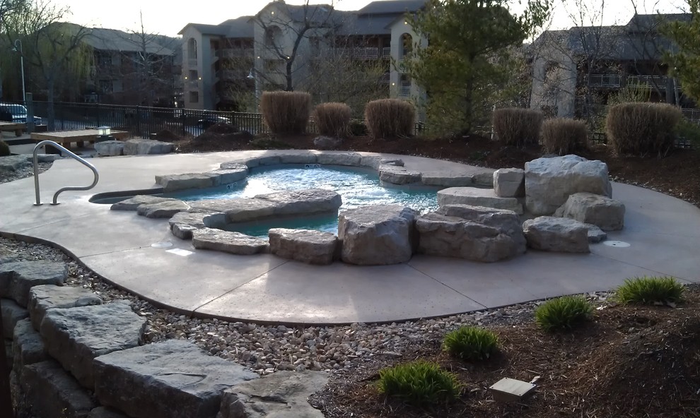 Hot tub - large rustic courtyard stamped concrete and custom-shaped natural hot tub idea in Other