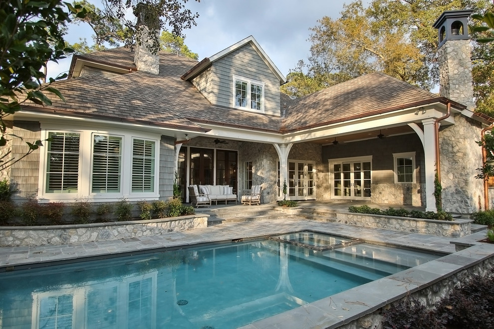 Modelo de piscina natural clásica de tamaño medio rectangular en patio trasero con adoquines de piedra natural