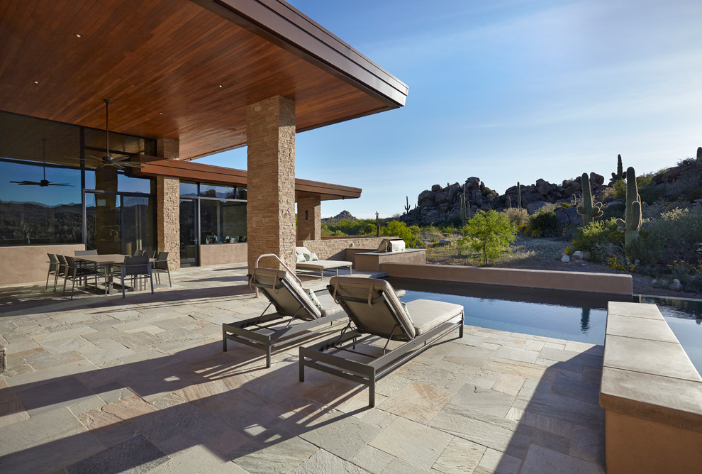 Foto de piscinas y jacuzzis elevados actuales grandes en forma de L en patio trasero con adoquines de piedra natural