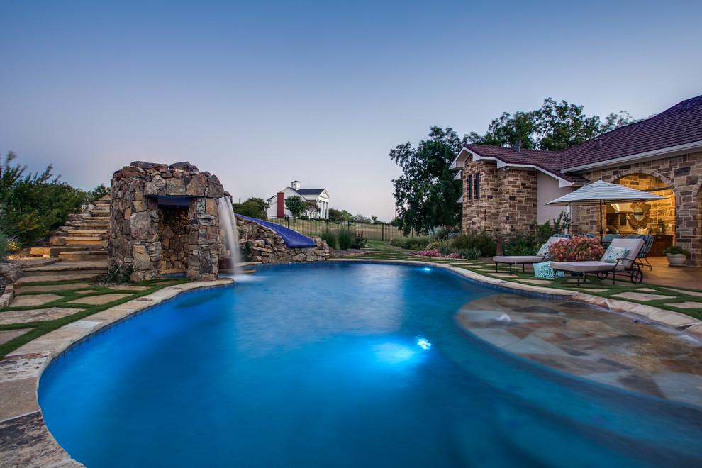 Ejemplo de piscina con fuente rústica a medida en patio trasero con adoquines de piedra natural