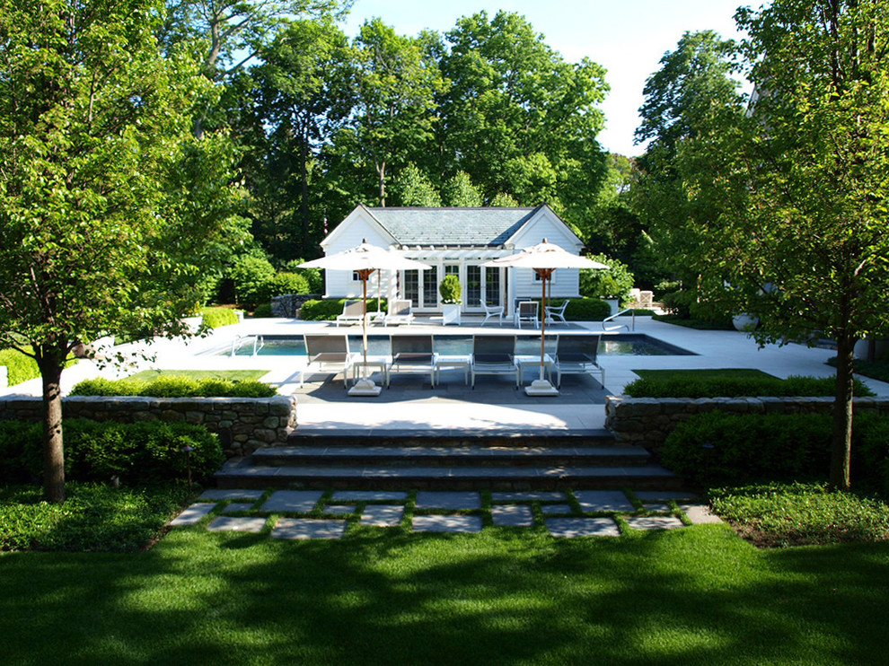 На фото: большой прямоугольный бассейн на заднем дворе в классическом стиле с домиком у бассейна и покрытием из каменной брусчатки с