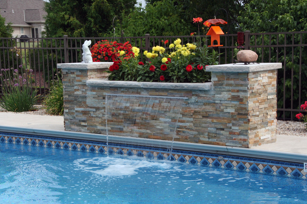 Foto på en pool på baksidan av huset, med en fontän och naturstensplattor