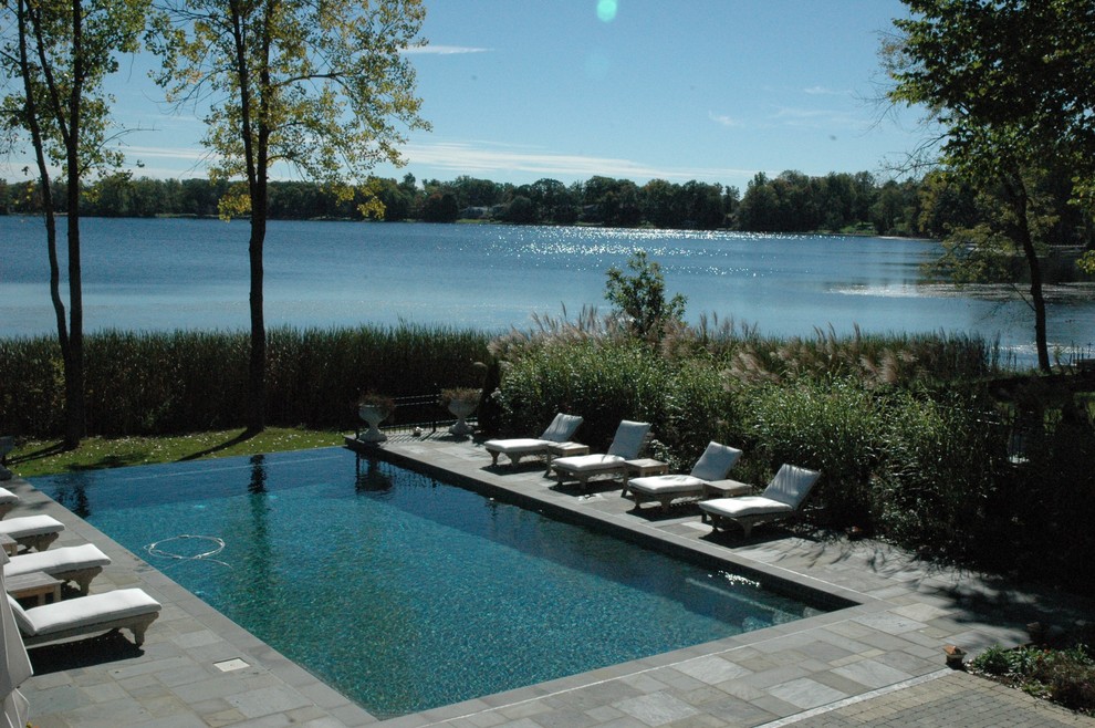 Diseño de piscinas y jacuzzis infinitos clásicos renovados grandes rectangulares en patio trasero con adoquines de piedra natural