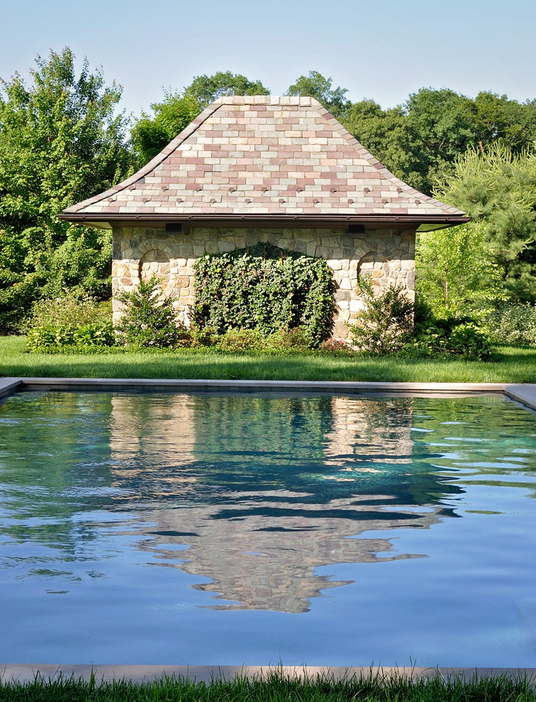 Modelo de piscina con fuente alargada de estilo americano grande rectangular en patio trasero con adoquines de hormigón