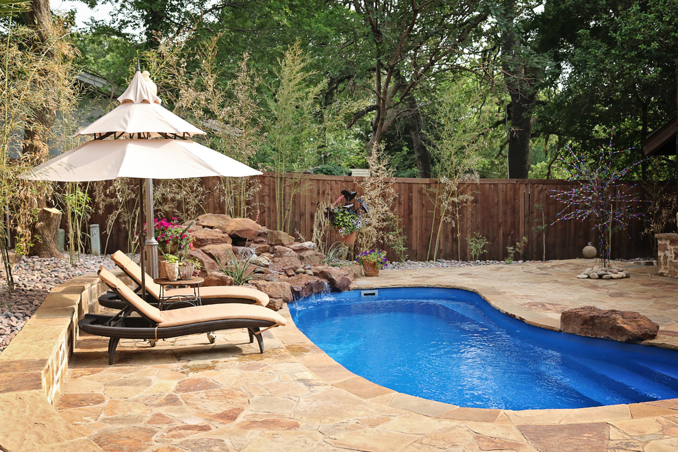 Mittelgroßer Klassischer Schwimmteich hinter dem Haus in Nierenform mit Wasserspiel und Natursteinplatten in Dallas