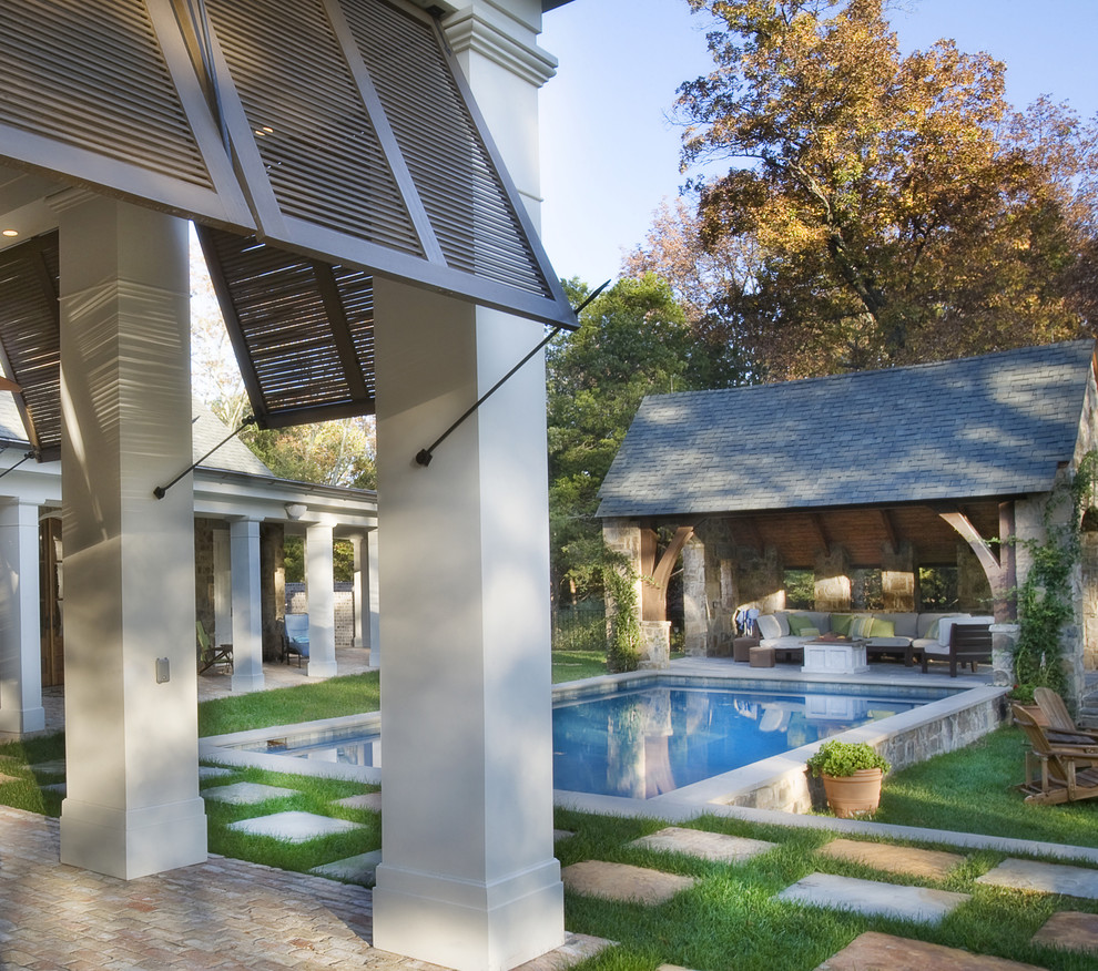 Exempel på en klassisk rektangulär gårdsplan med pool, med marksten i betong och poolhus