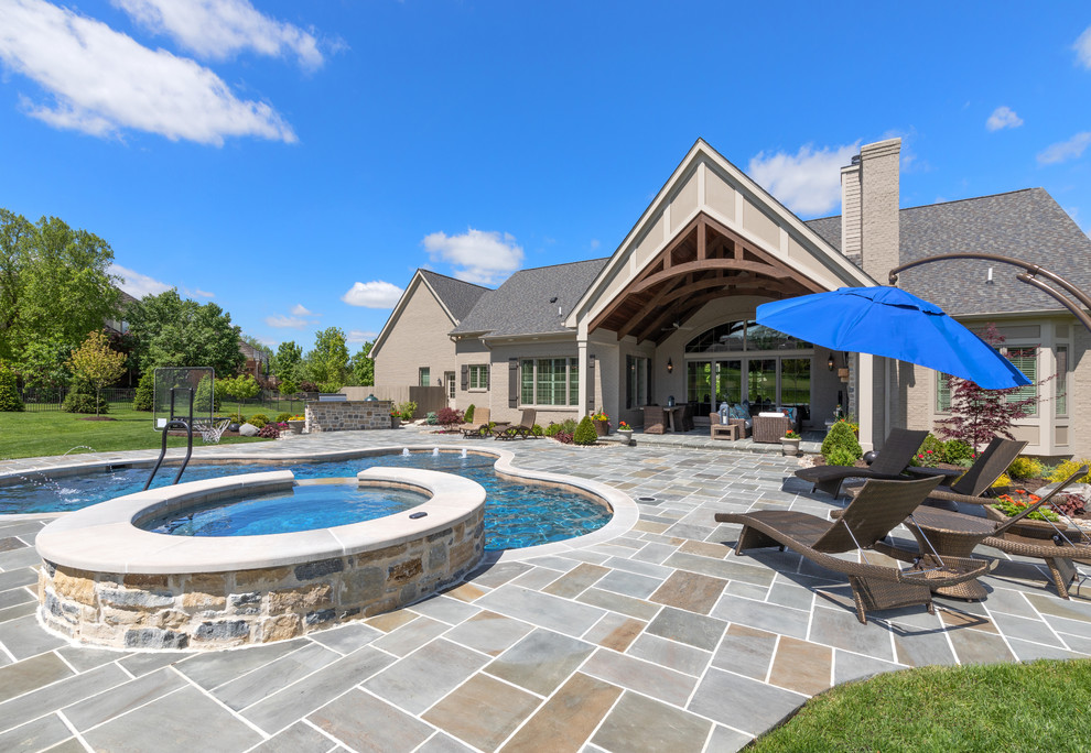 Immagine di una piscina naturale chic personalizzata di medie dimensioni e dietro casa con una vasca idromassaggio e pavimentazioni in pietra naturale