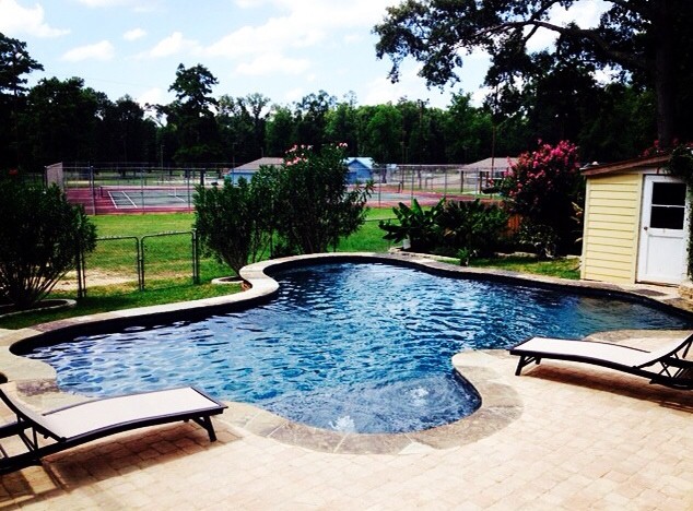 Imagen de piscina infinita clásica pequeña a medida en patio trasero con adoquines de hormigón