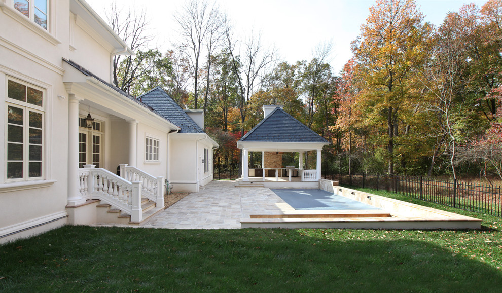Ejemplo de casa de la piscina y piscina alargada clásica extra grande rectangular en patio lateral con adoquines de piedra natural