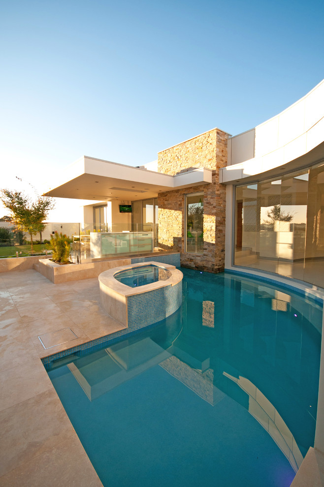 Bild på en mellanstor funkis anpassad pool på baksidan av huset, med naturstensplattor och spabad
