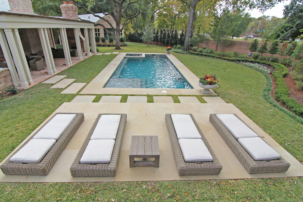 Foto di una grande piscina monocorsia design rettangolare dietro casa con una vasca idromassaggio e lastre di cemento