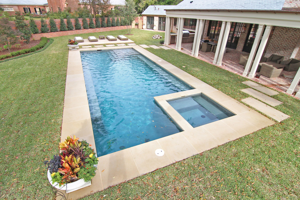 Idee per una grande piscina monocorsia minimal rettangolare dietro casa con una vasca idromassaggio e lastre di cemento