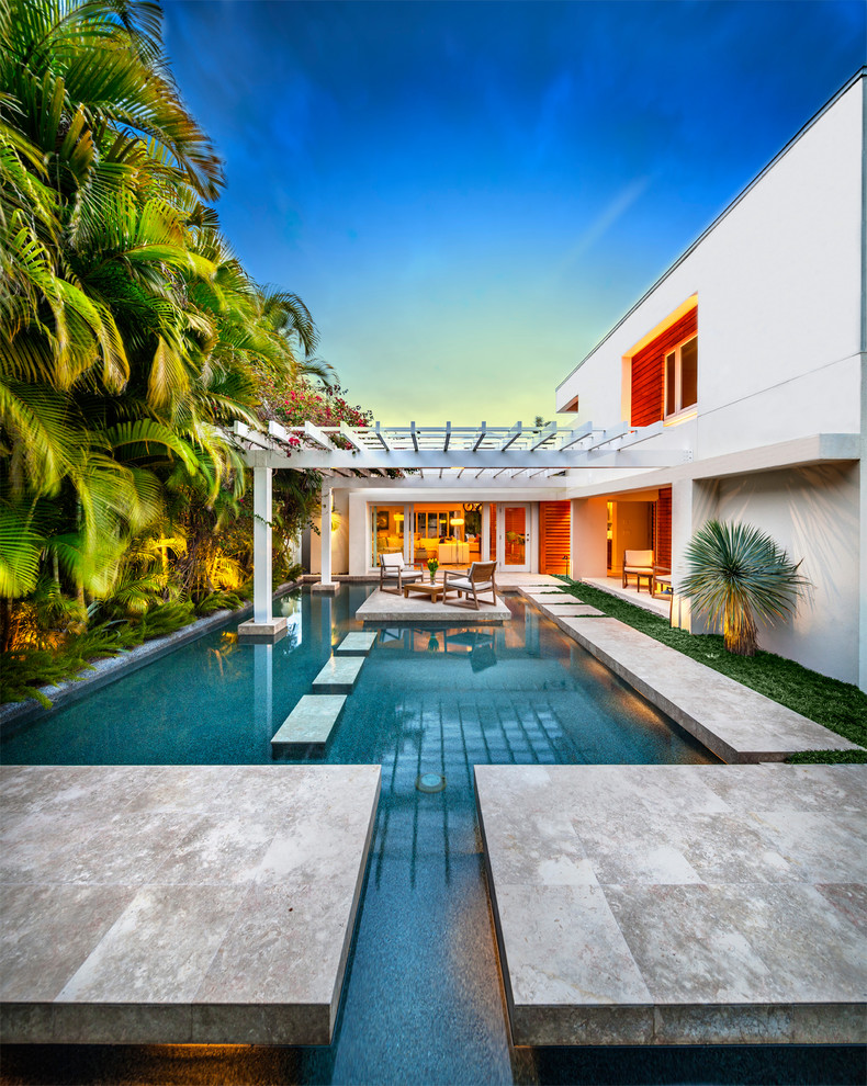 Imagen de piscina tropical rectangular con suelo de baldosas