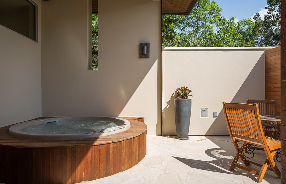This is an example of a contemporary swimming pool in Austin with a water feature and natural stone paving.