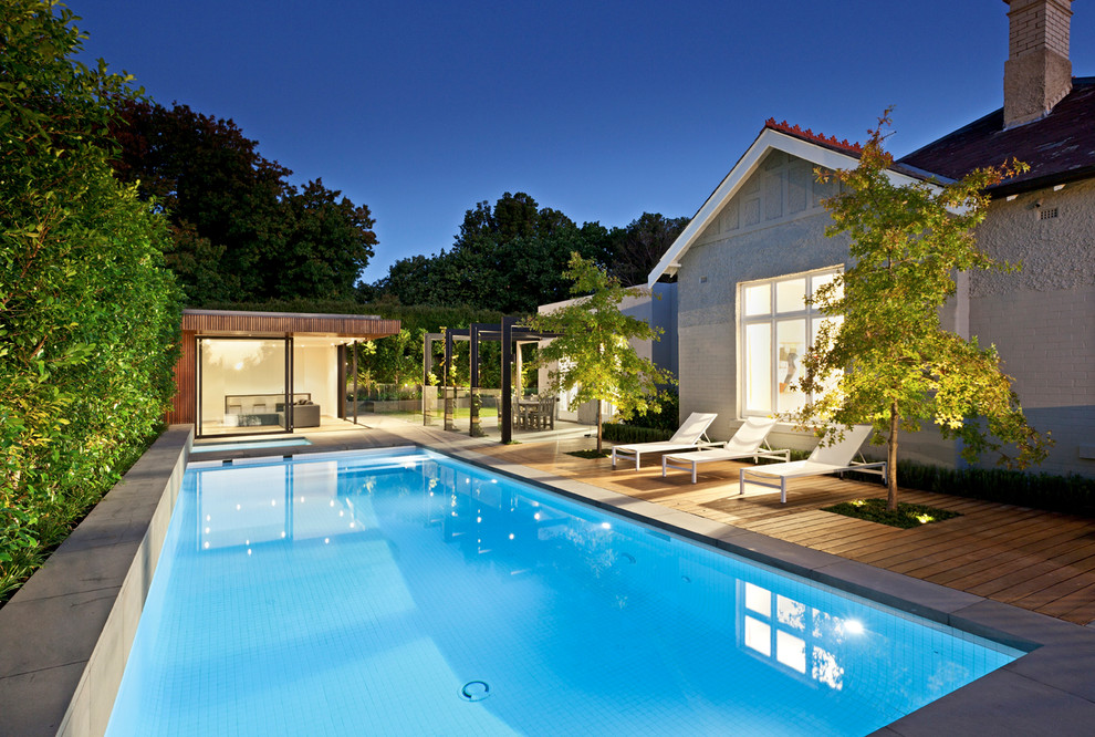 На фото: спортивный, прямоугольный бассейн на заднем дворе в стиле модернизм с домиком у бассейна и покрытием из каменной брусчатки