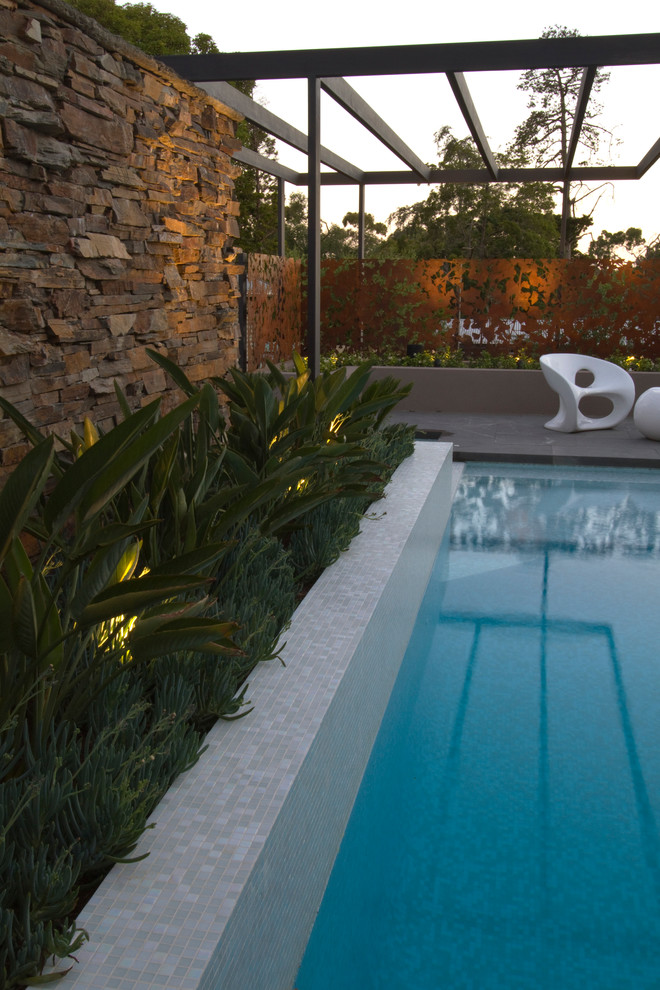 Mittelgroßes Modernes Sportbecken hinter dem Haus in rechteckiger Form mit Wasserspiel und Natursteinplatten in Sydney