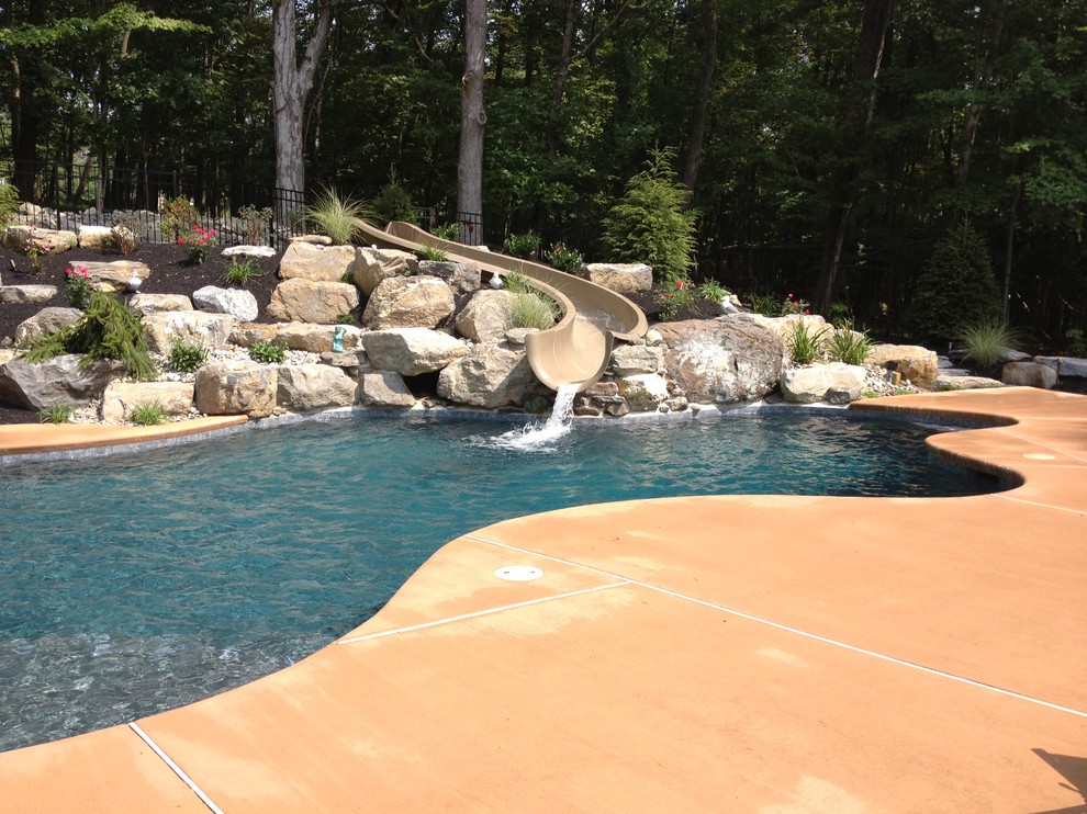 Réalisation d'une piscine naturelle et arrière tradition sur mesure avec une terrasse en bois et un bain bouillonnant.
