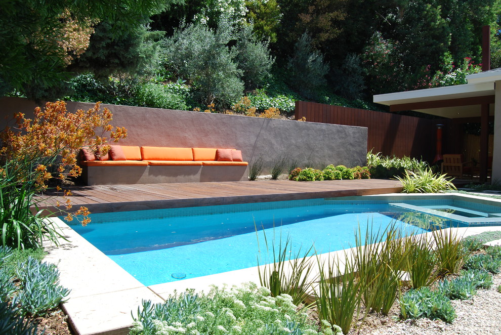 Diseño de piscinas y jacuzzis modernos a medida en patio trasero con entablado