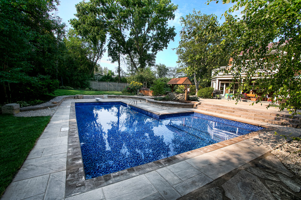 Idee per una grande piscina rustica a "L" dietro casa con una dépendance a bordo piscina e piastrelle