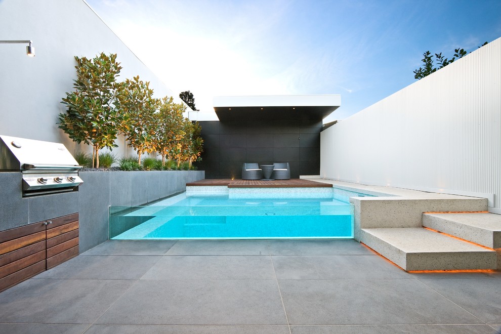 Ejemplo de piscina actual pequeña rectangular en patio trasero con adoquines de hormigón