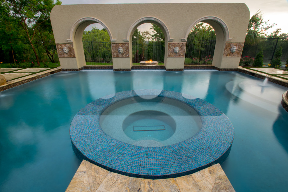 Imagen de piscina con tobogán infinita moderna grande a medida en patio trasero con adoquines de piedra natural