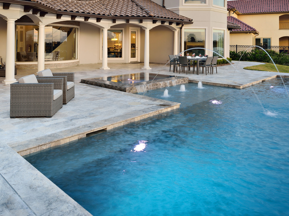 Foto di una grande piscina a sfioro infinito tradizionale personalizzata dietro casa con una vasca idromassaggio e pavimentazioni in pietra naturale