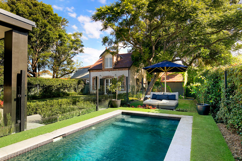 Classic back rectangular lengths swimming pool in Sydney with a pool house and natural stone paving.
