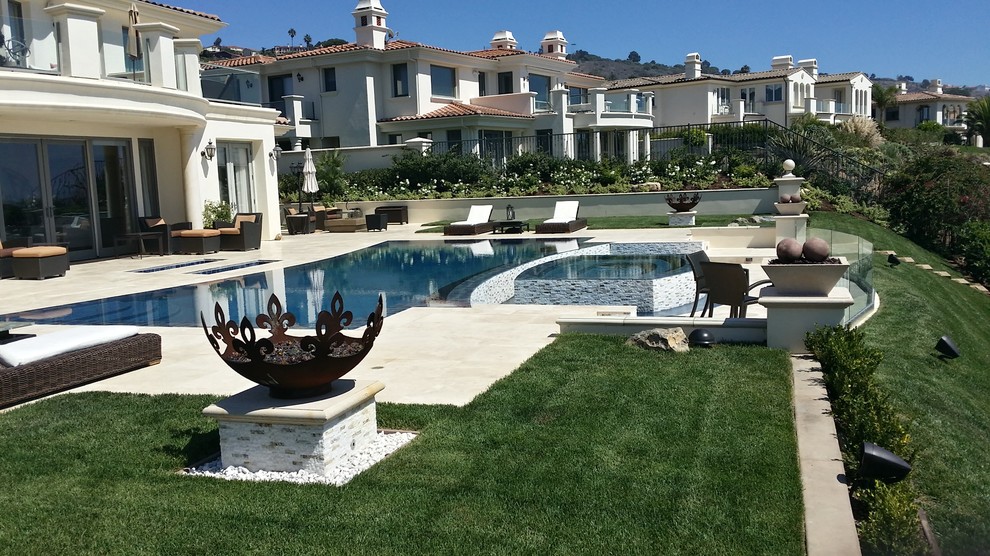 Immagine di una grande piscina a sfioro infinito design personalizzata dietro casa con pavimentazioni in pietra naturale