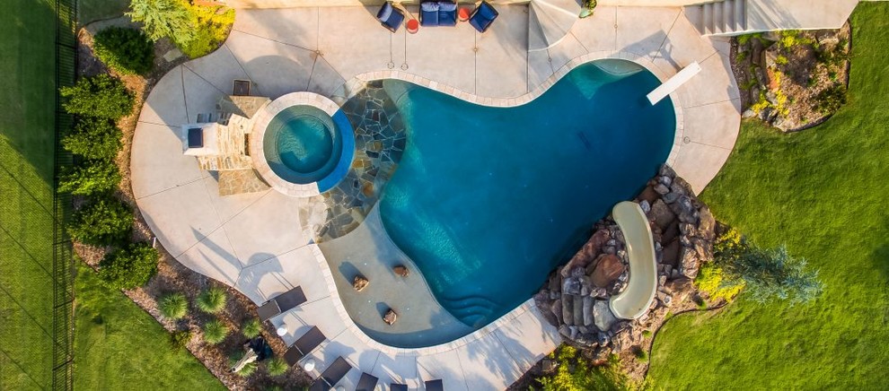 На фото: огромный бассейн произвольной формы на заднем дворе в морском стиле с водной горкой
