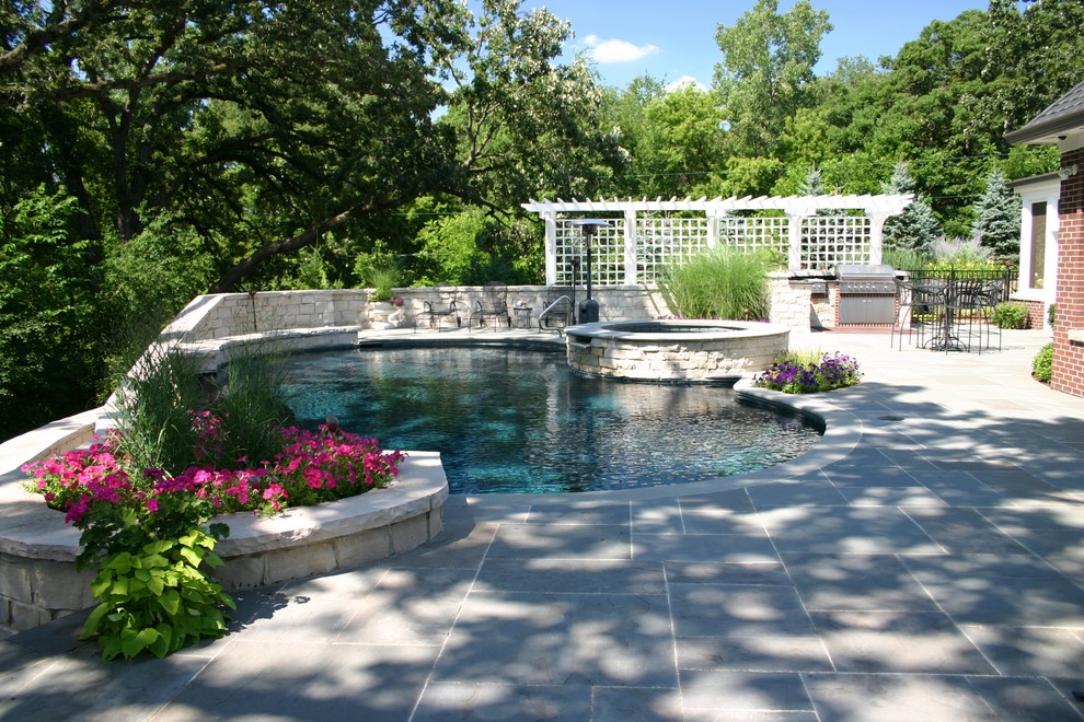 Foto di una grande piscina a sfioro infinito tradizionale a "C" dietro casa con pavimentazioni in pietra naturale e fontane
