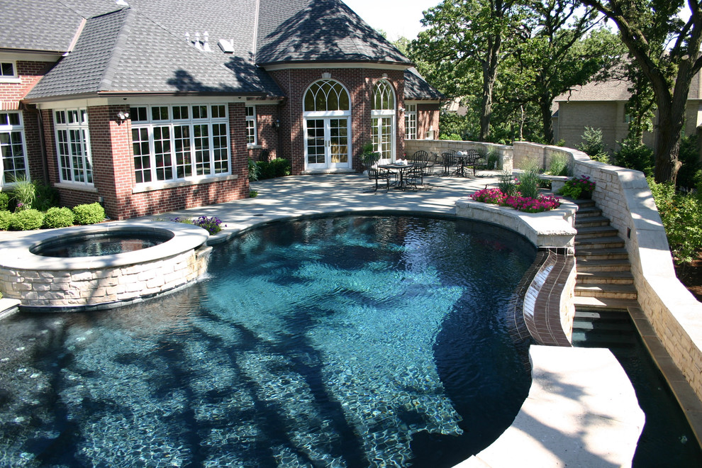 Large elegant backyard stone and kidney-shaped infinity hot tub photo in Chicago