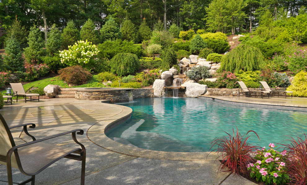 Modelo de piscina con fuente clásica grande a medida en patio trasero con adoquines de hormigón