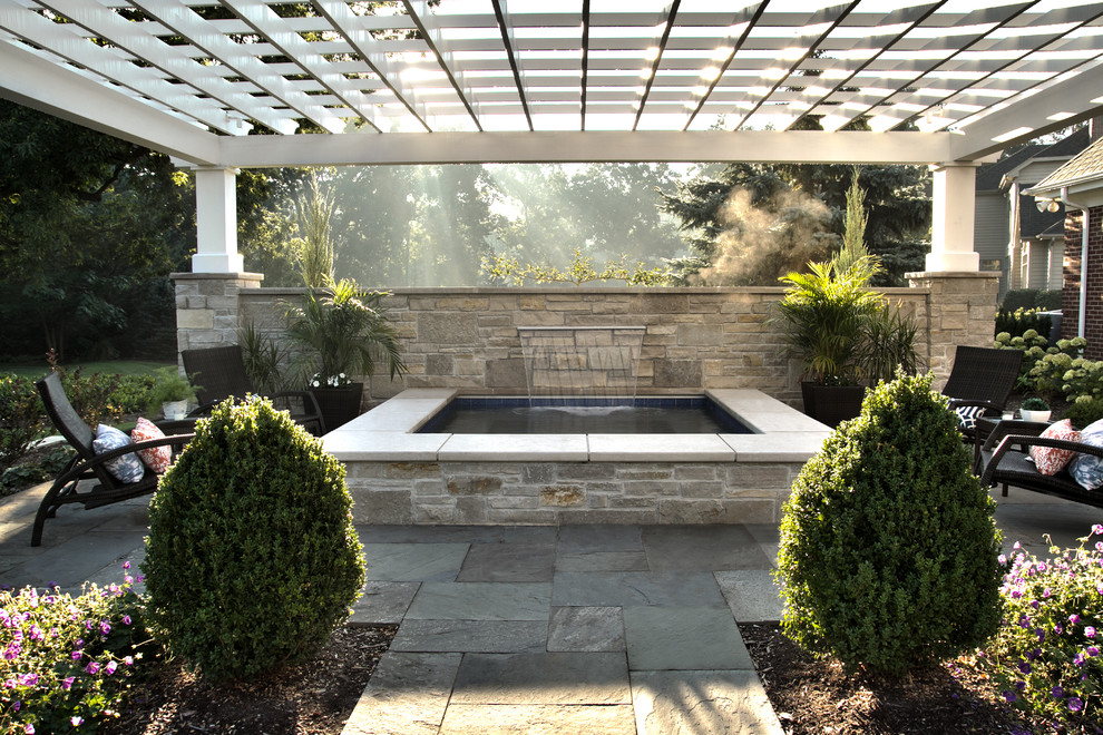 Imagen de piscinas y jacuzzis elevados clásicos pequeños rectangulares en patio trasero con adoquines de piedra natural