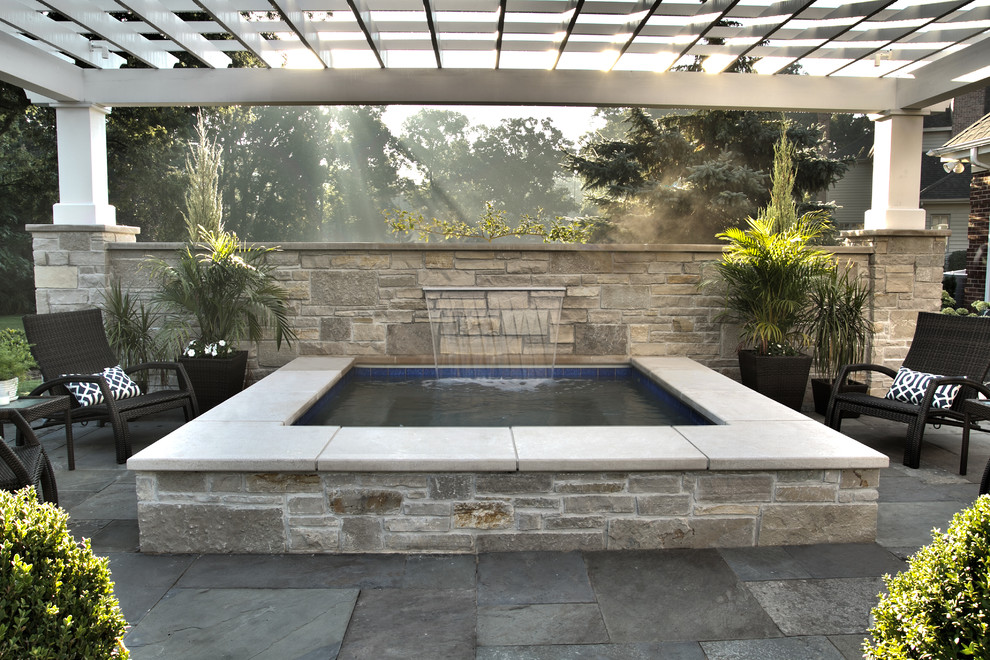 Immagine di una piccola piscina fuori terra classica rettangolare dietro casa con una vasca idromassaggio e pavimentazioni in pietra naturale