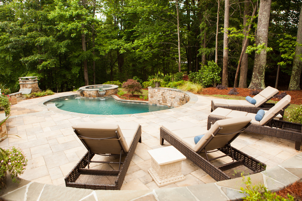 Foto di una grande piscina monocorsia tradizionale a "C" dietro casa con una vasca idromassaggio e pavimentazioni in pietra naturale