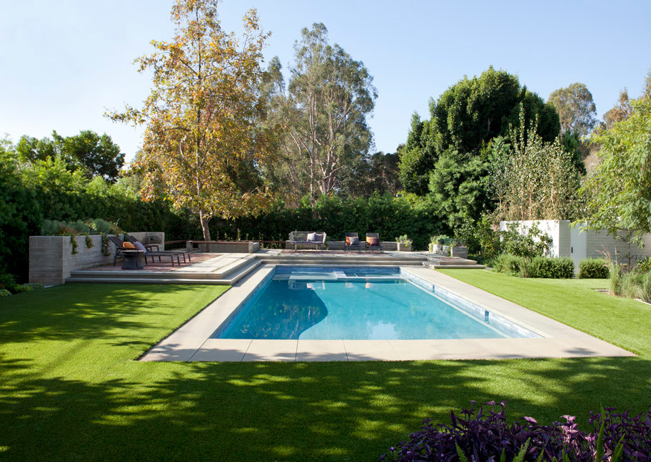 Foto de piscinas y jacuzzis alargados retro grandes rectangulares en patio trasero con adoquines de hormigón