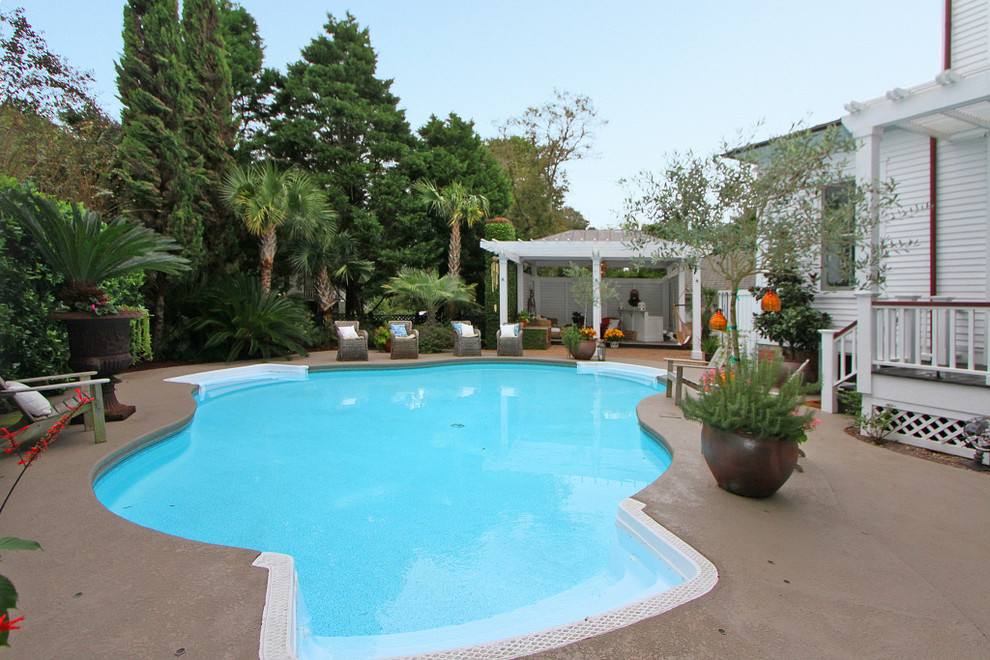 Пример оригинального дизайна: большой бассейн произвольной формы на заднем дворе в классическом стиле с покрытием из бетонных плит