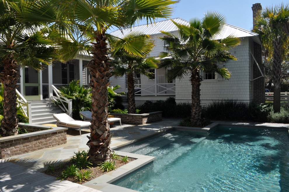 Imagen de piscina natural costera rectangular en patio con adoquines de piedra natural