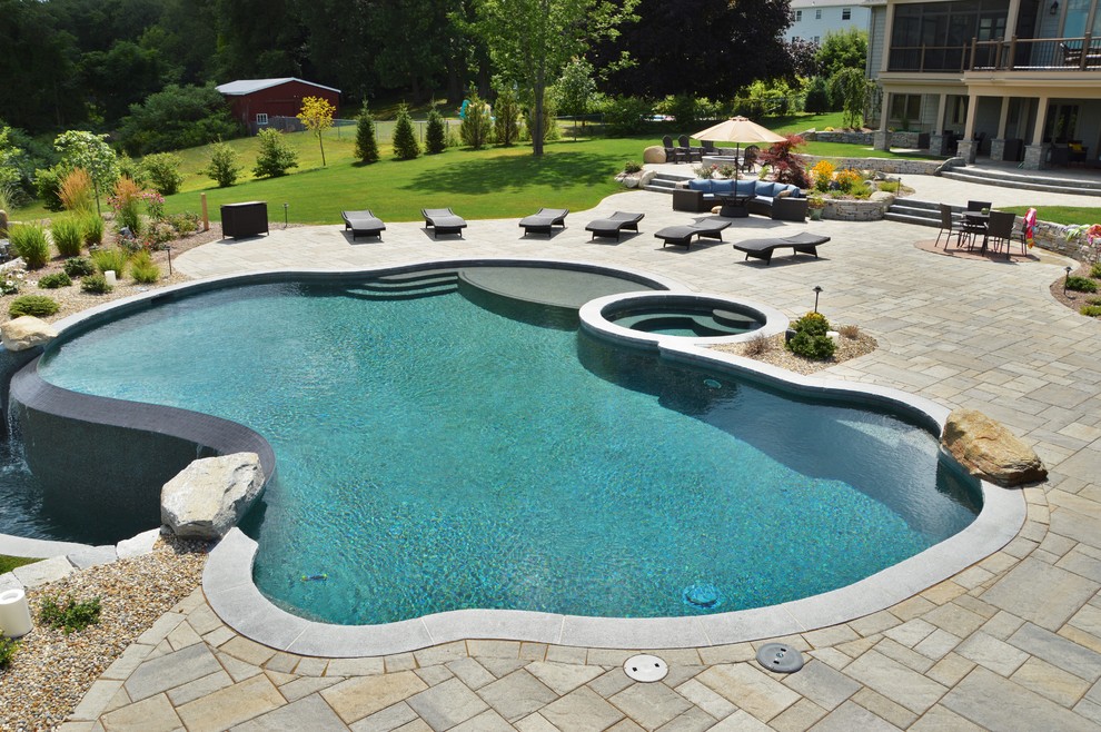 Immagine di una grande piscina chic personalizzata dietro casa con una vasca idromassaggio e cemento stampato