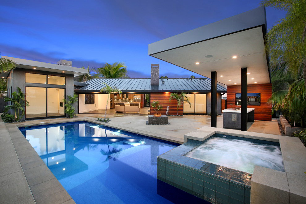 Esempio di una piscina design rettangolare dietro casa con una vasca idromassaggio e lastre di cemento