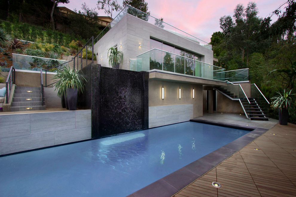 Diseño de casa de la piscina y piscina alargada actual grande rectangular en patio trasero con suelo de baldosas