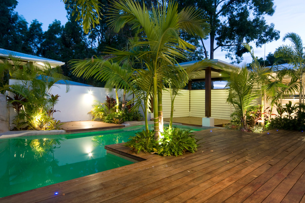 Immagine di una piscina tropicale di medie dimensioni e dietro casa con pedane