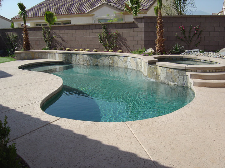 Immagine di una piscina naturale tropicale di medie dimensioni e dietro casa con pavimentazioni in pietra naturale e una vasca idromassaggio