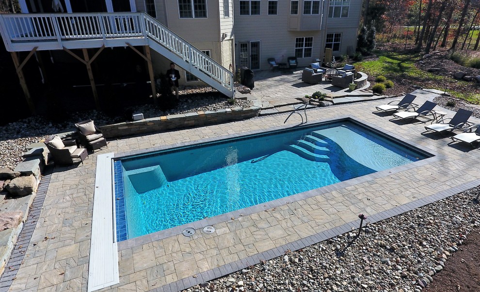 Ejemplo de piscina rústica de tamaño medio rectangular en patio trasero con adoquines de hormigón