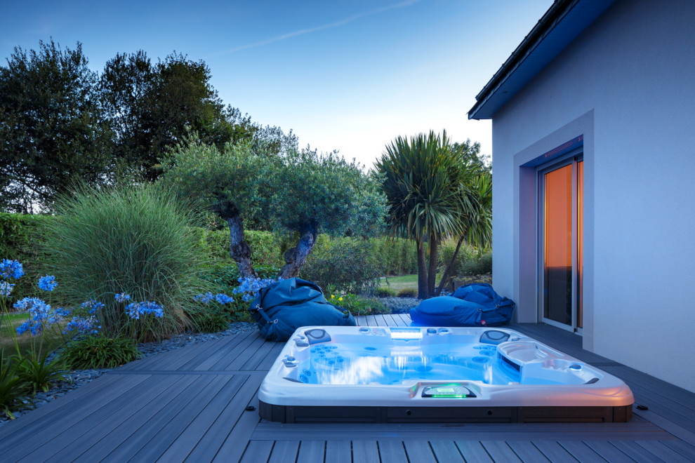 Idée de décoration pour une piscine arrière tradition avec un bain bouillonnant et une terrasse en bois.