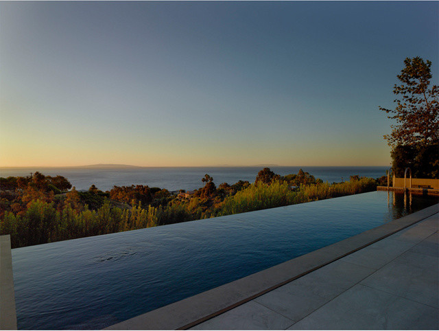 Immagine di una grande piscina a sfioro infinito minimalista rettangolare dietro casa con una vasca idromassaggio e piastrelle
