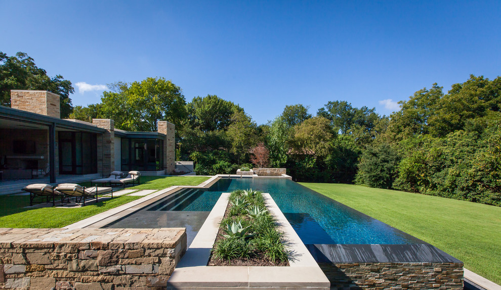 Foto di una piscina a sfioro infinito minimalista rettangolare di medie dimensioni e dietro casa con fontane e pavimentazioni in pietra naturale
