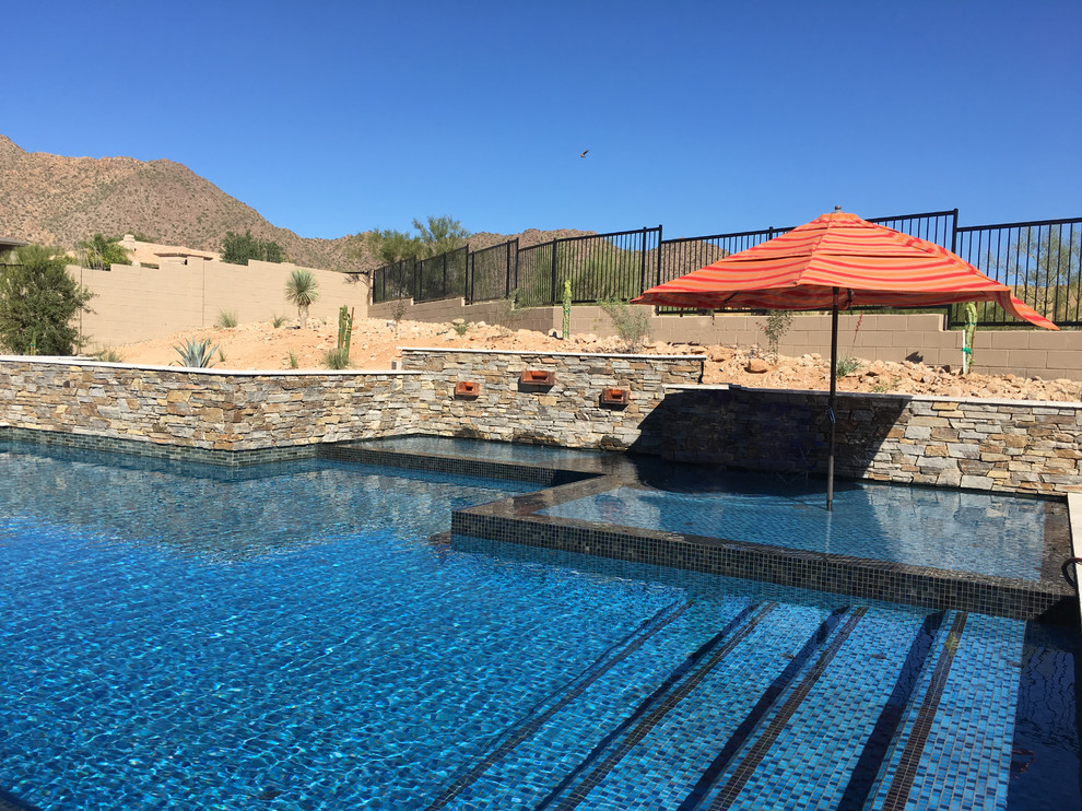 Immagine di una grande piscina monocorsia design rettangolare dietro casa con una vasca idromassaggio e cemento stampato