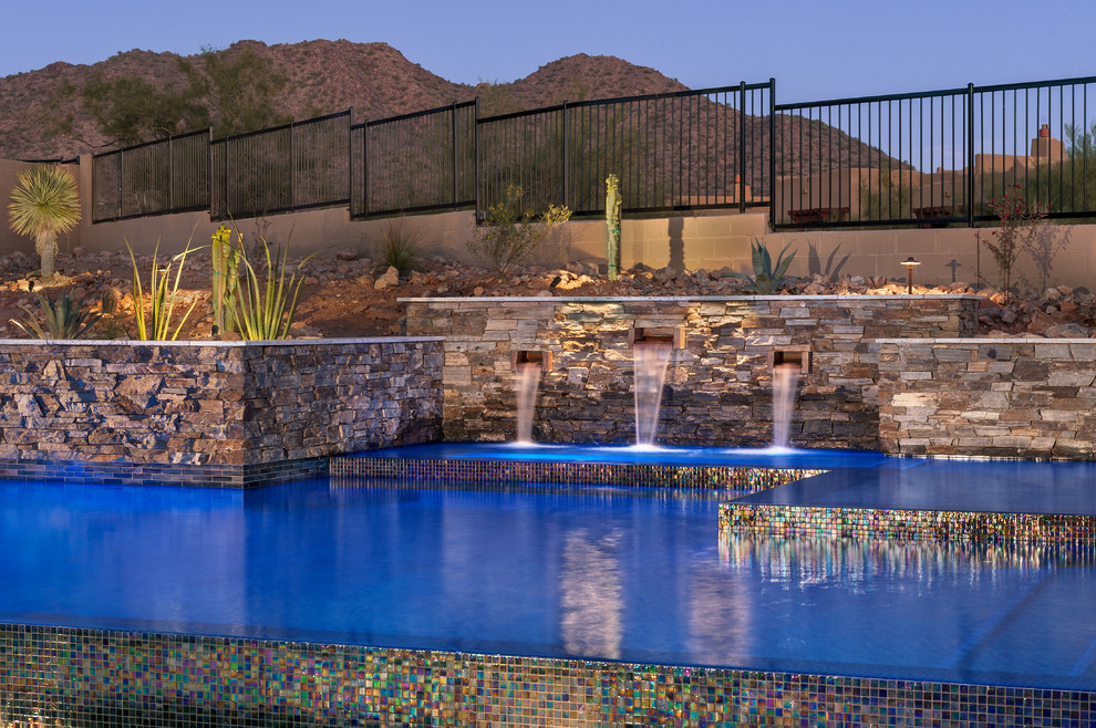 Esempio di una piscina a sfioro infinito contemporanea personalizzata di medie dimensioni e dietro casa con fontane e pavimentazioni in pietra naturale