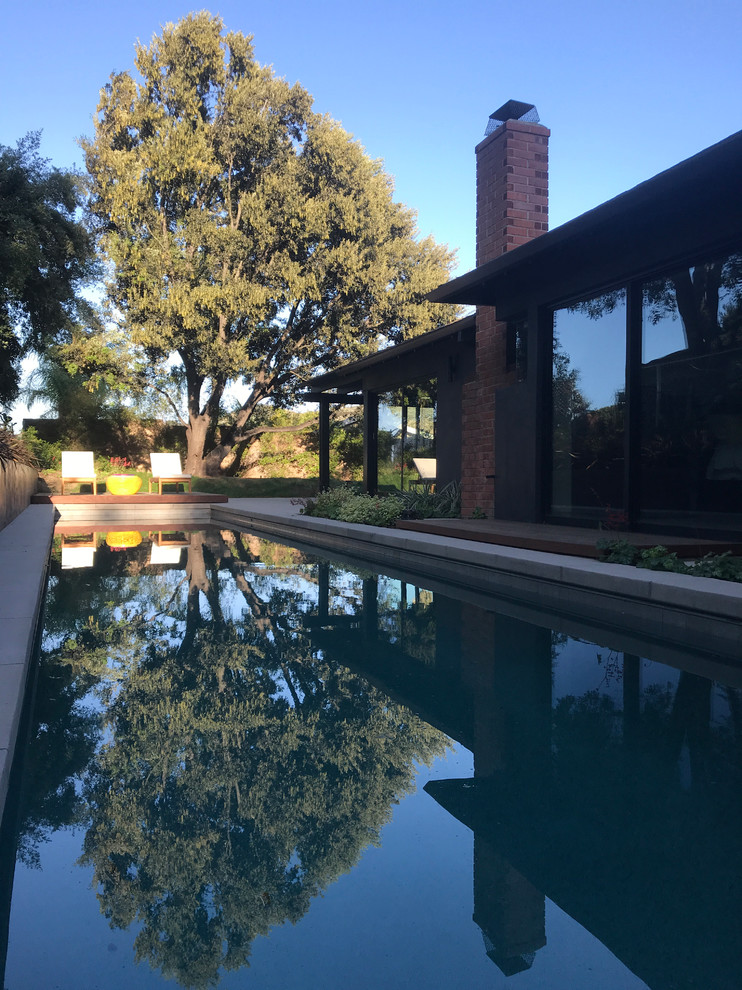 Diseño de piscina alargada vintage de tamaño medio rectangular en patio trasero con losas de hormigón